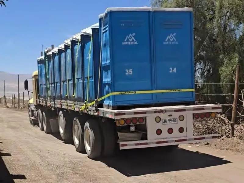 Rampla cargada con baños químicos de Norte Vital en traslado hacia una obra