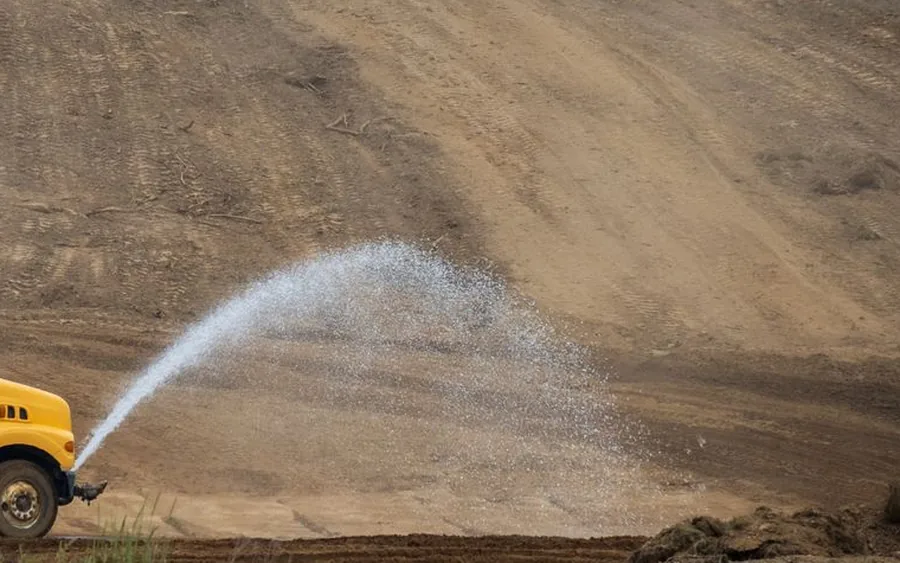 Camión aljibe humectando terreno en una faena de movimiento de tierras
