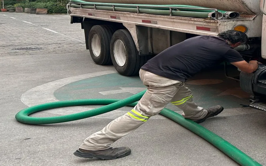Operador conectando manguera a un camión para retiro de aguas servidas